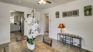 A dining area with a wooden table, chairs, a ceiling fan, and a kitchen in the background. - 1 Mi to Dtwn! Lubbock Home w/ Private Patio & Yard (Lubbock)