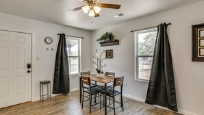 A dining area with a wooden table and chairs, a ceiling fan, and a window with curtains. - 1 Mi to Dtwn! Lubbock Home w/ Private Patio & Yard (Lubbock)