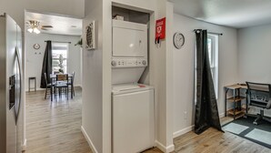A compact kitchen with a refrigerator, a microwave, and a stove. There is a dining area with a table and chairs, and a window with curtains. - 1 Mi to Dtwn! Lubbock Home w/ Private Patio & Yard (Lubbock)