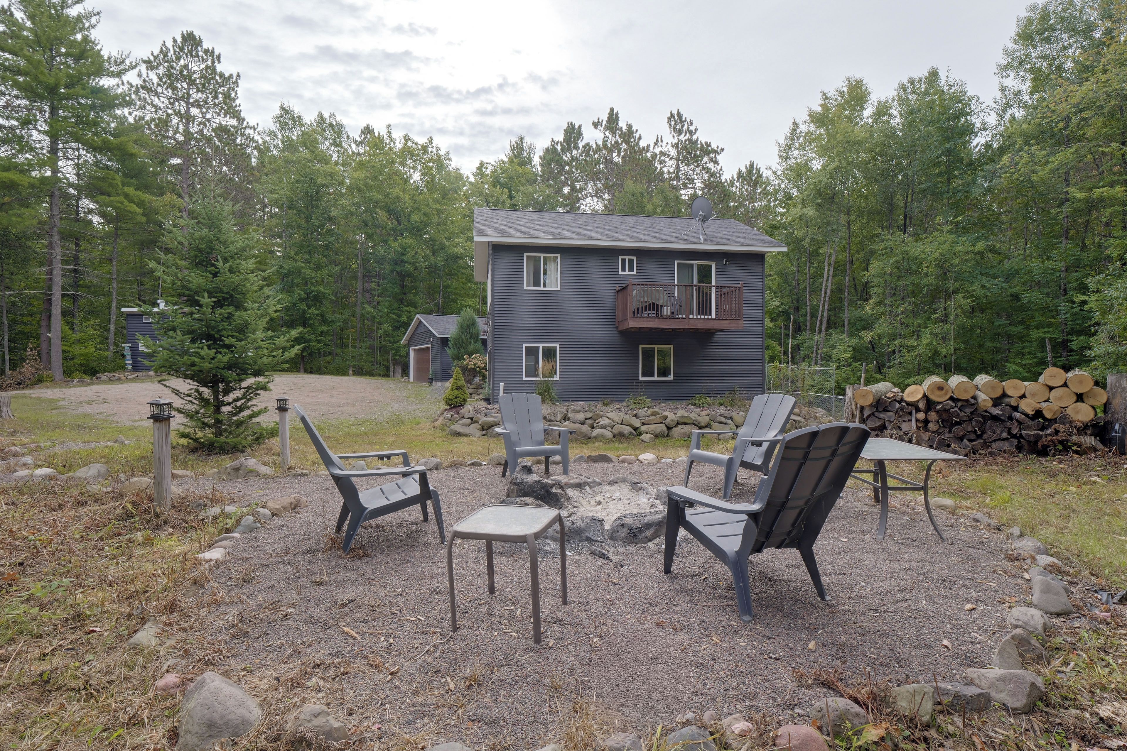 A two-story house with a balcony, surrounded by a gravel patio with outdoor furniture.