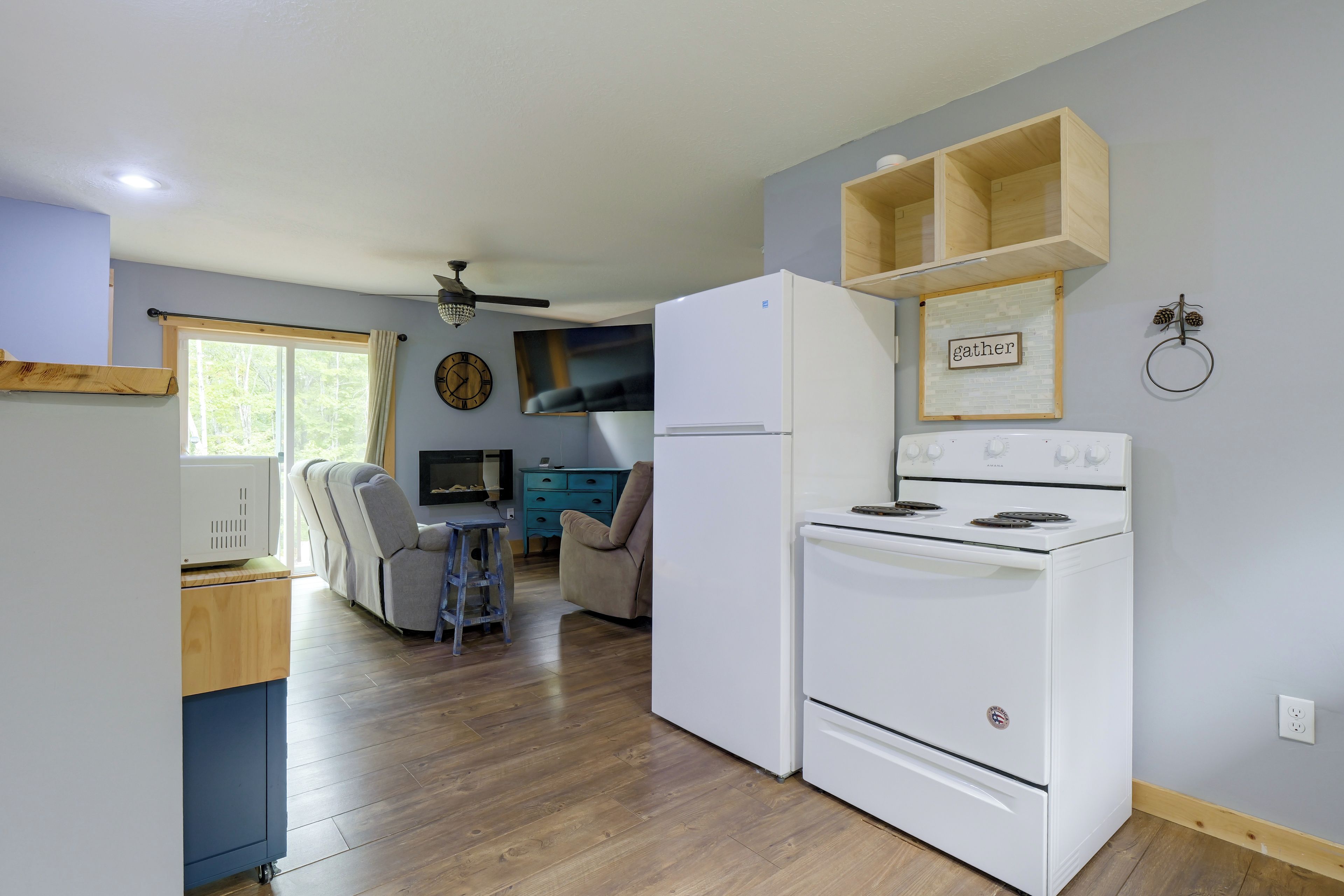 A compact kitchen with a refrigerator, stove, and a dining area with a chair and table.
