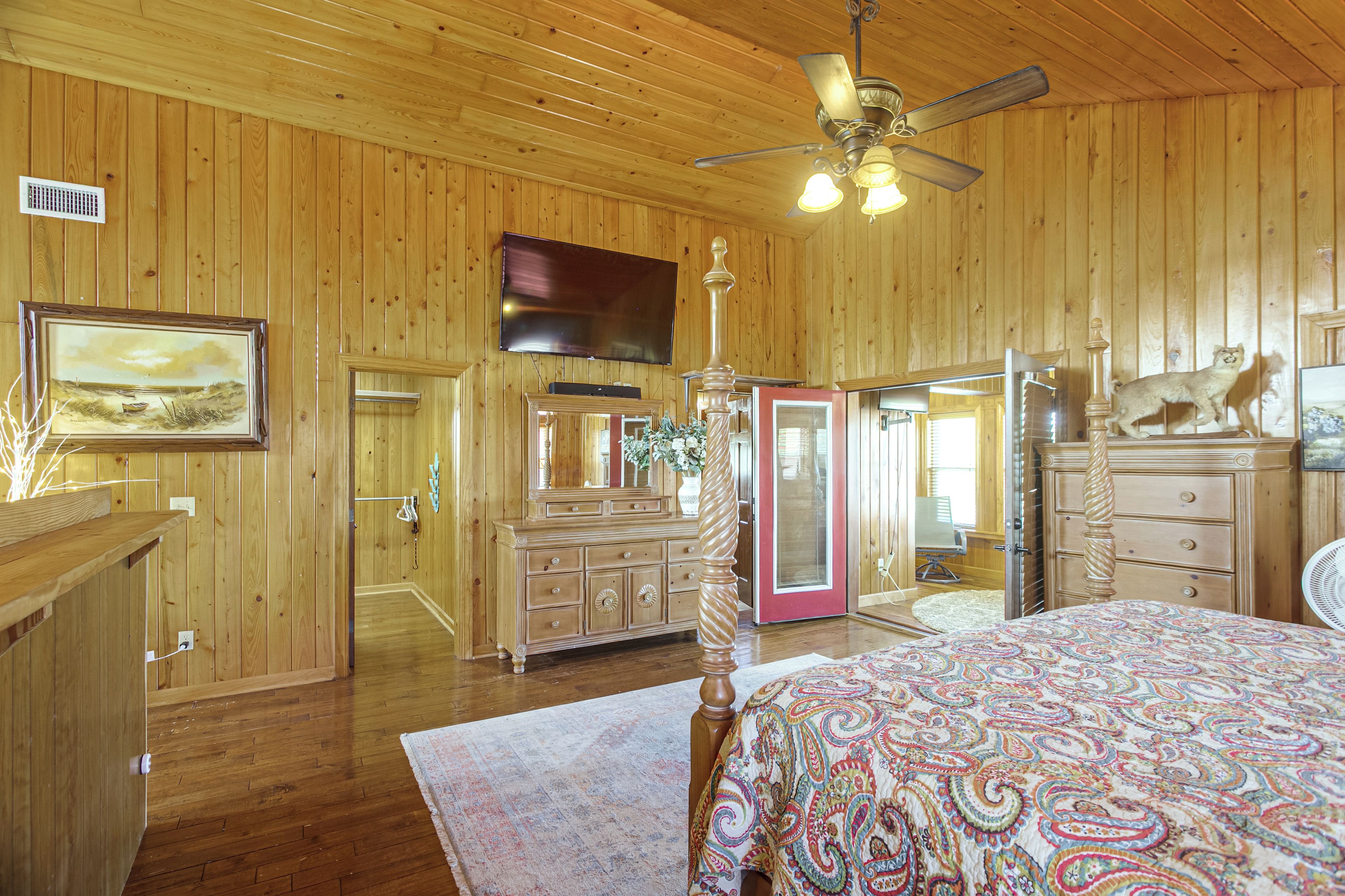 A wooden-paneled room with a bed, dresser, and a ceiling fan.