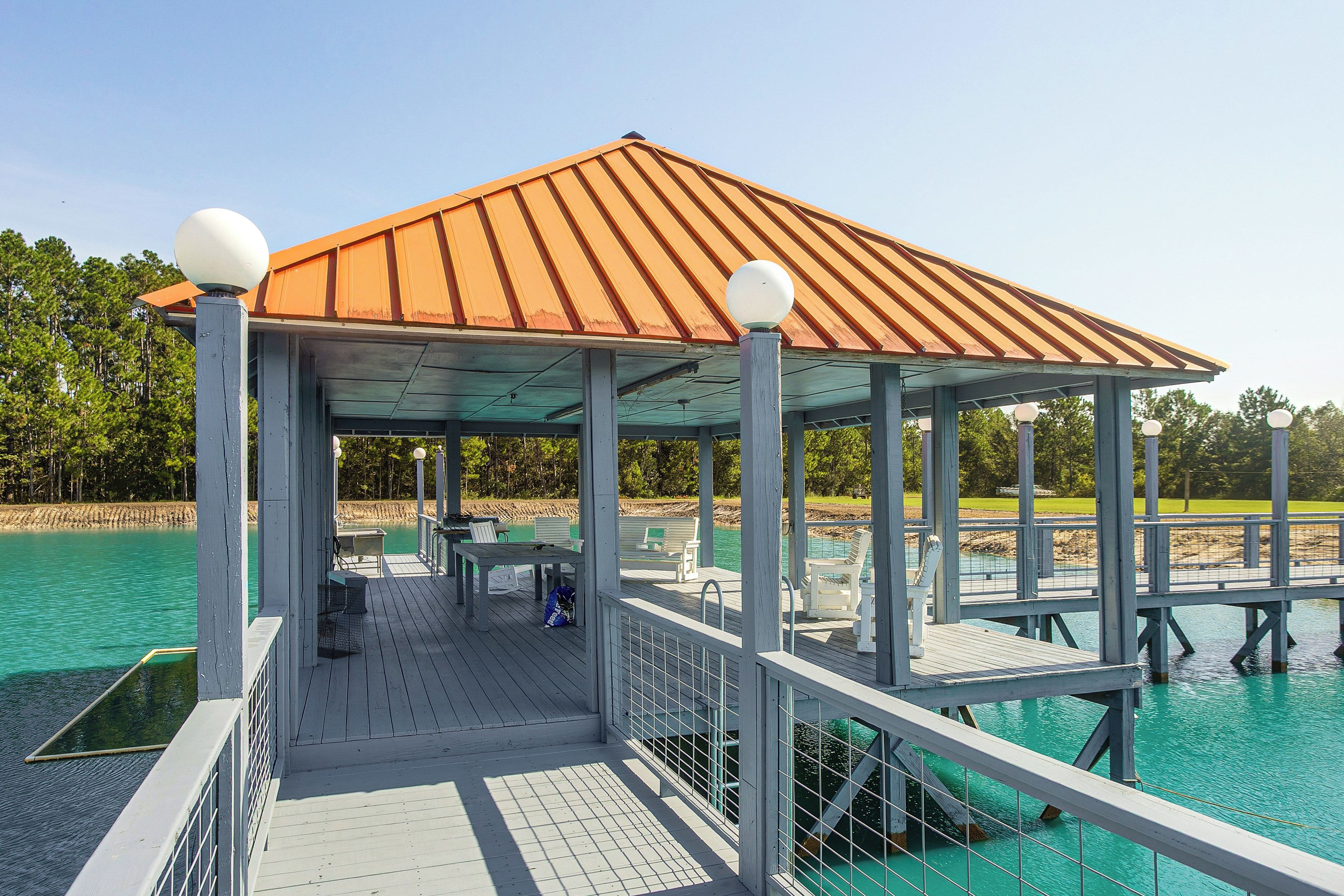 A covered outdoor area with a roof, seating, and a railing overlooking a body of water.