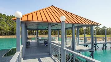 A covered outdoor area with a roof, seating, and a railing overlooking a body of water.