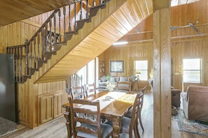A wooden interior with a staircase, dining area, and living space.