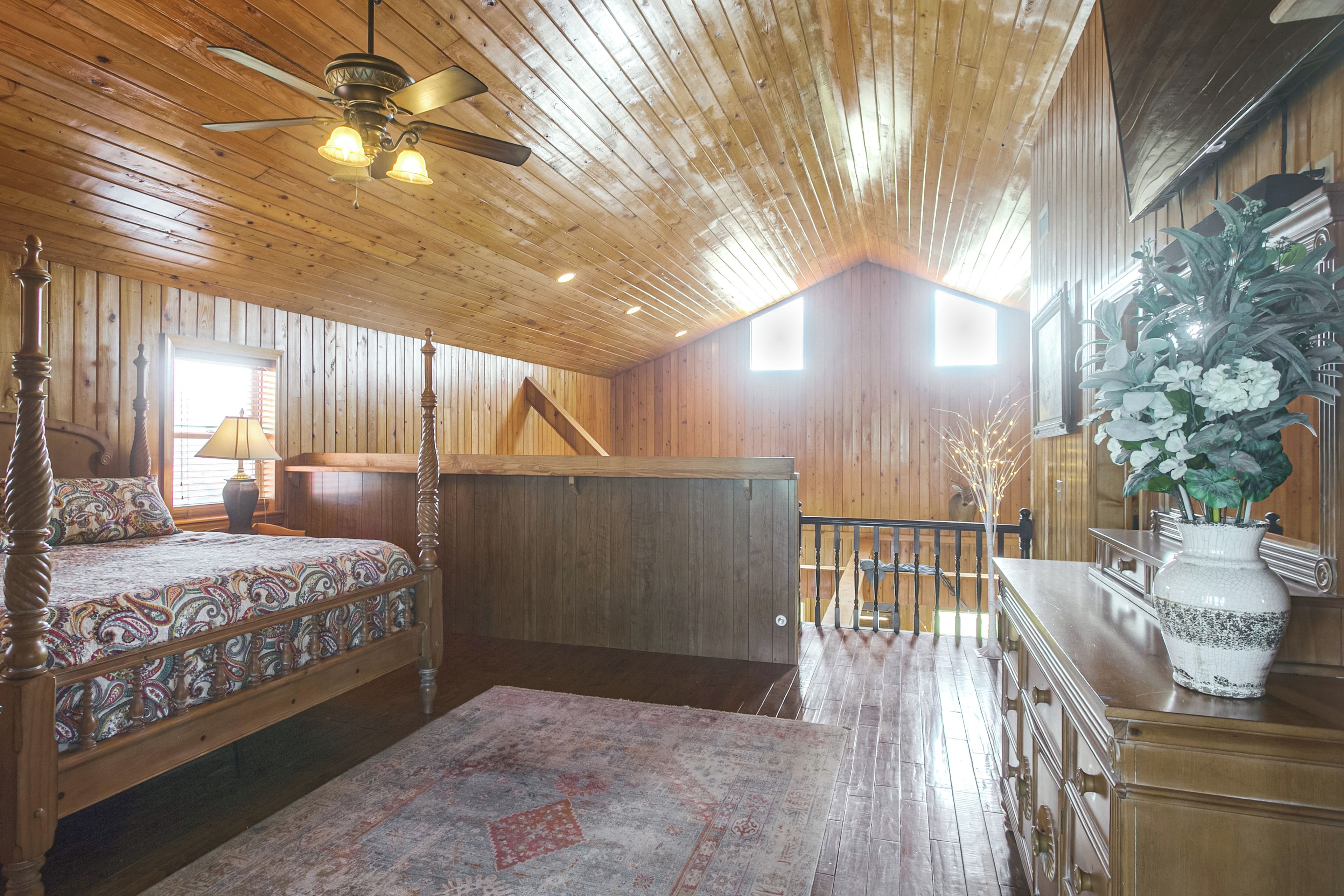 A wooden interior with a bed, a desk, and a staircase.