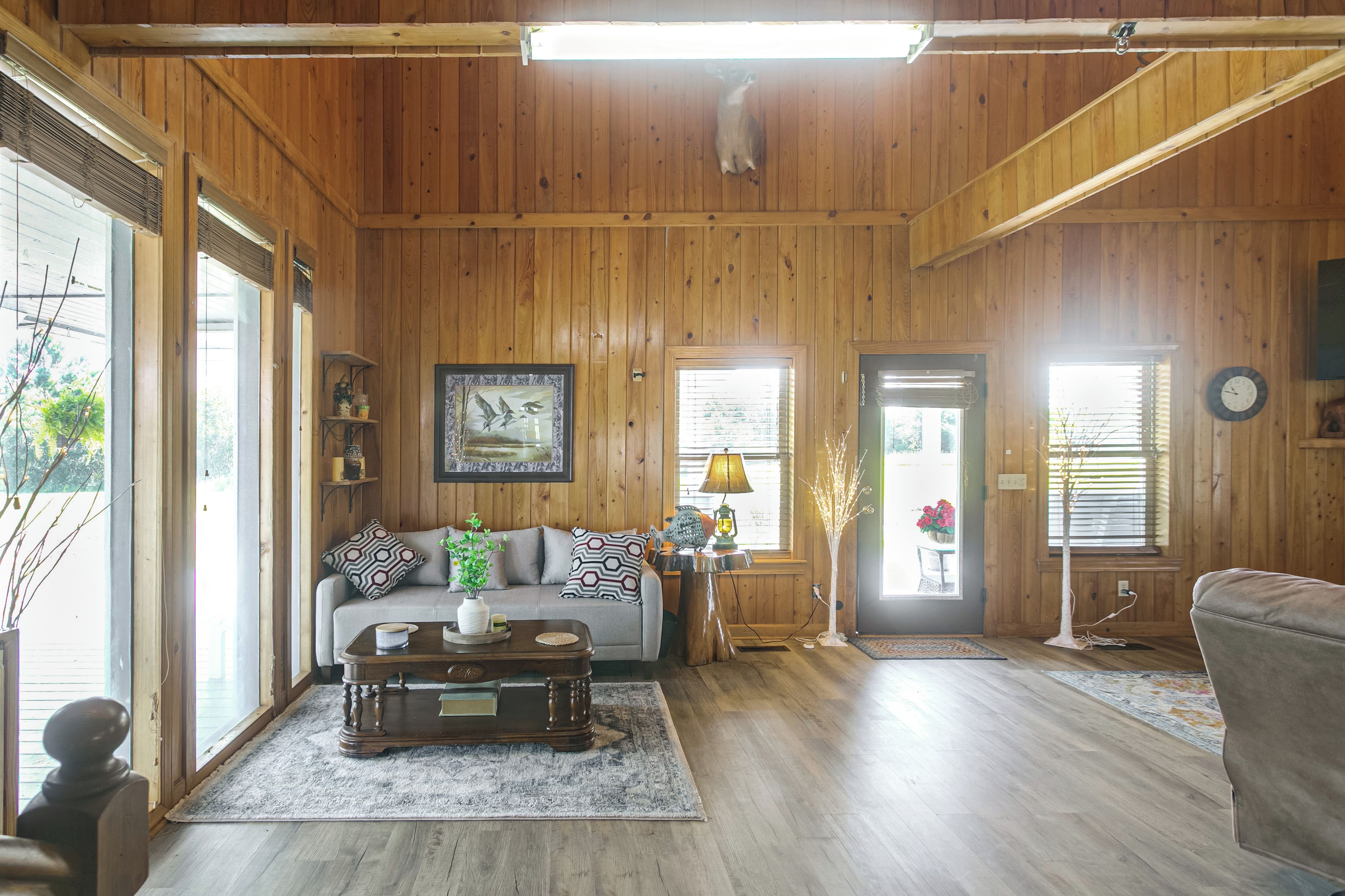A wooden-paneled room with a sofa, coffee table, and a lamp.
