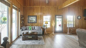 A wooden-paneled room with a sofa, coffee table, and a lamp. - Georgia Cabin Escape on 500 Acres (Nashville)