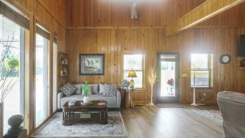 A wooden-paneled room with a sofa, coffee table, and a lamp.
