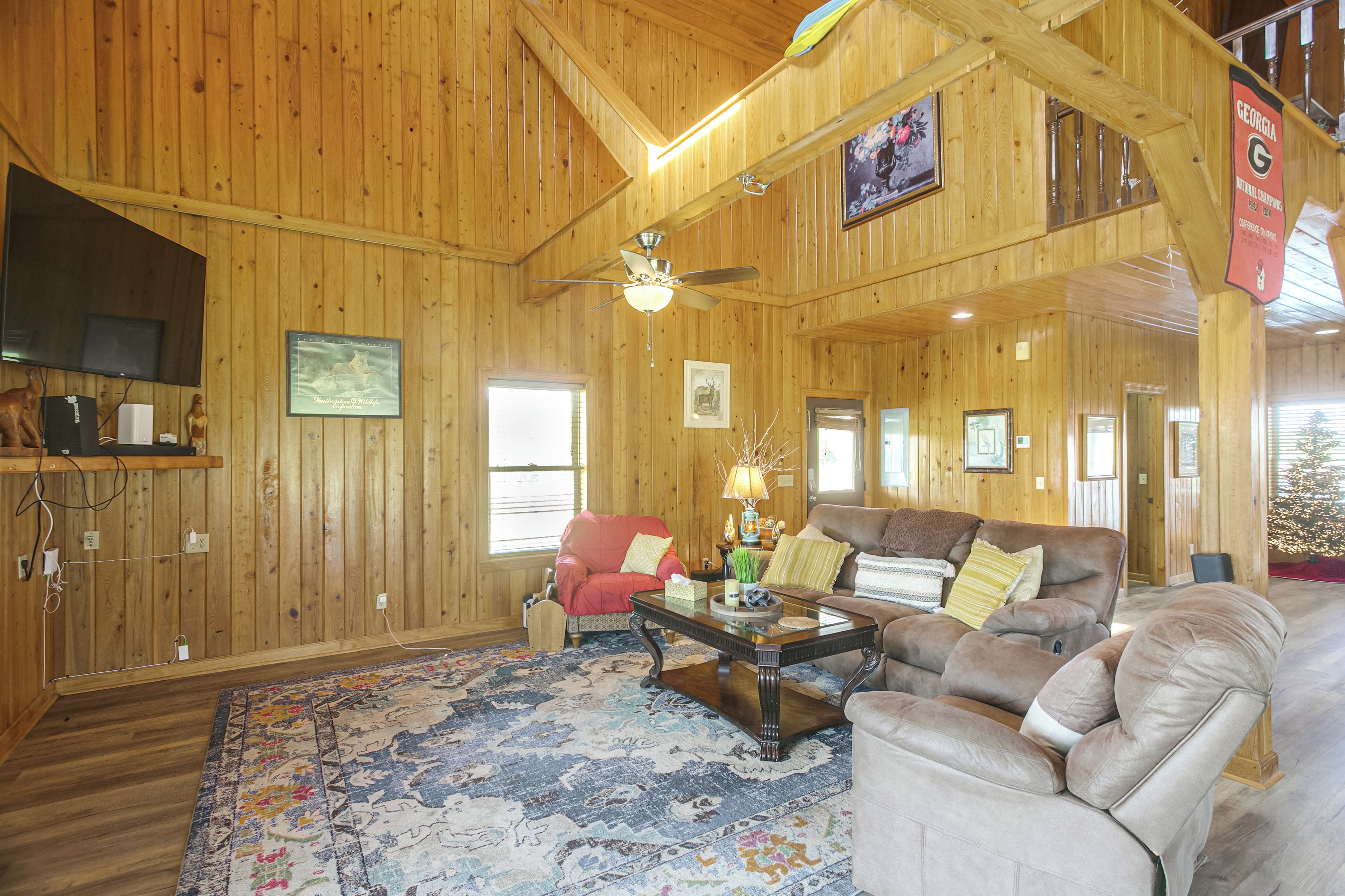 A wooden interior with a ceiling fan, a television, a sofa, and a coffee table.