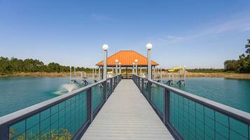 A pier leading to a building with a red roof, surrounded by water.