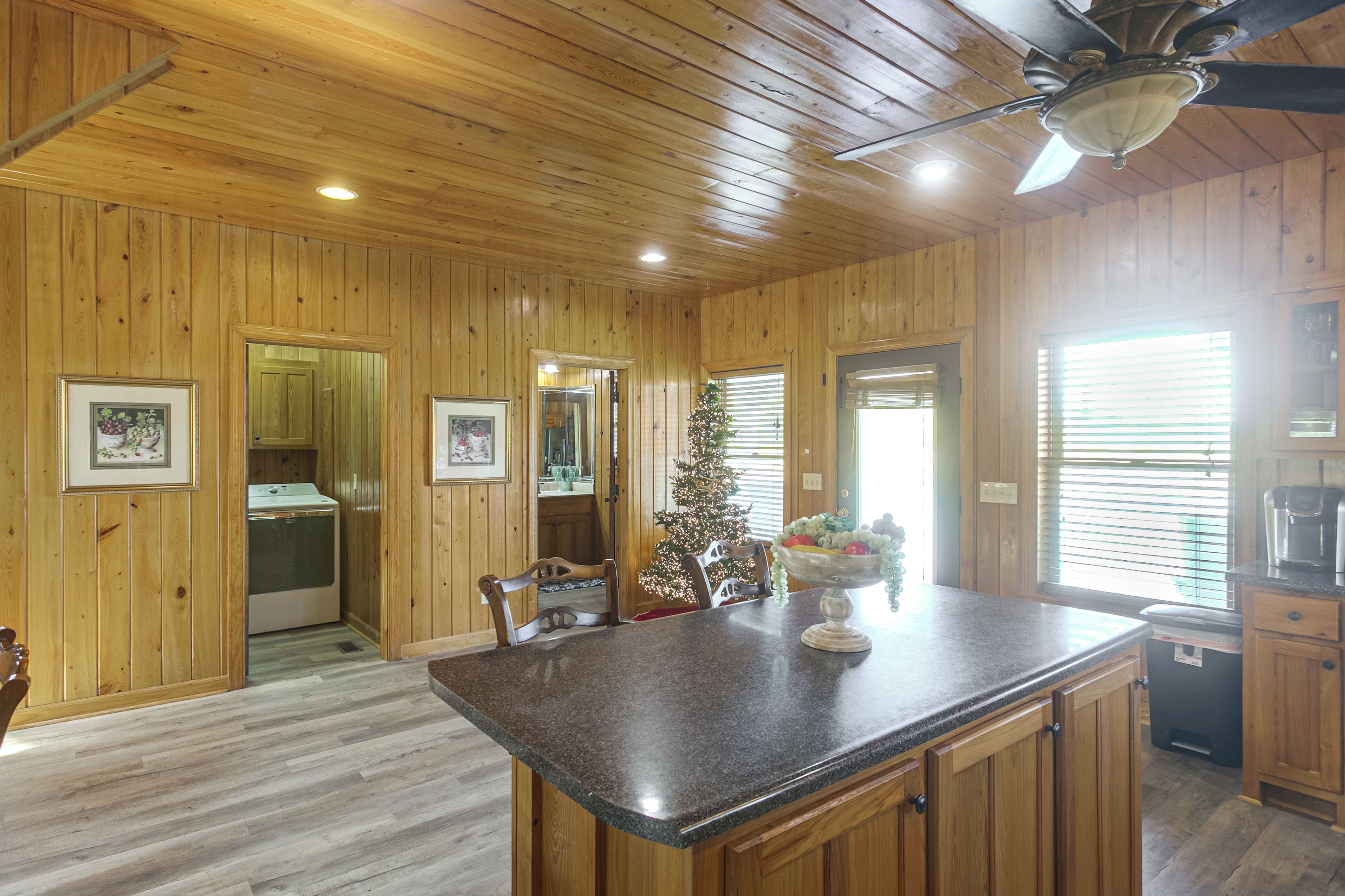 A kitchen with wooden walls, a granite countertop, and a ceiling fan.