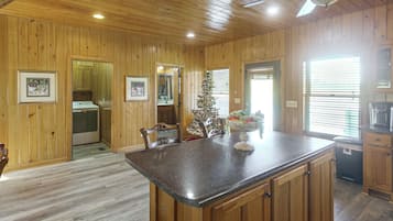 A kitchen with wooden walls, a granite countertop, and a ceiling fan.