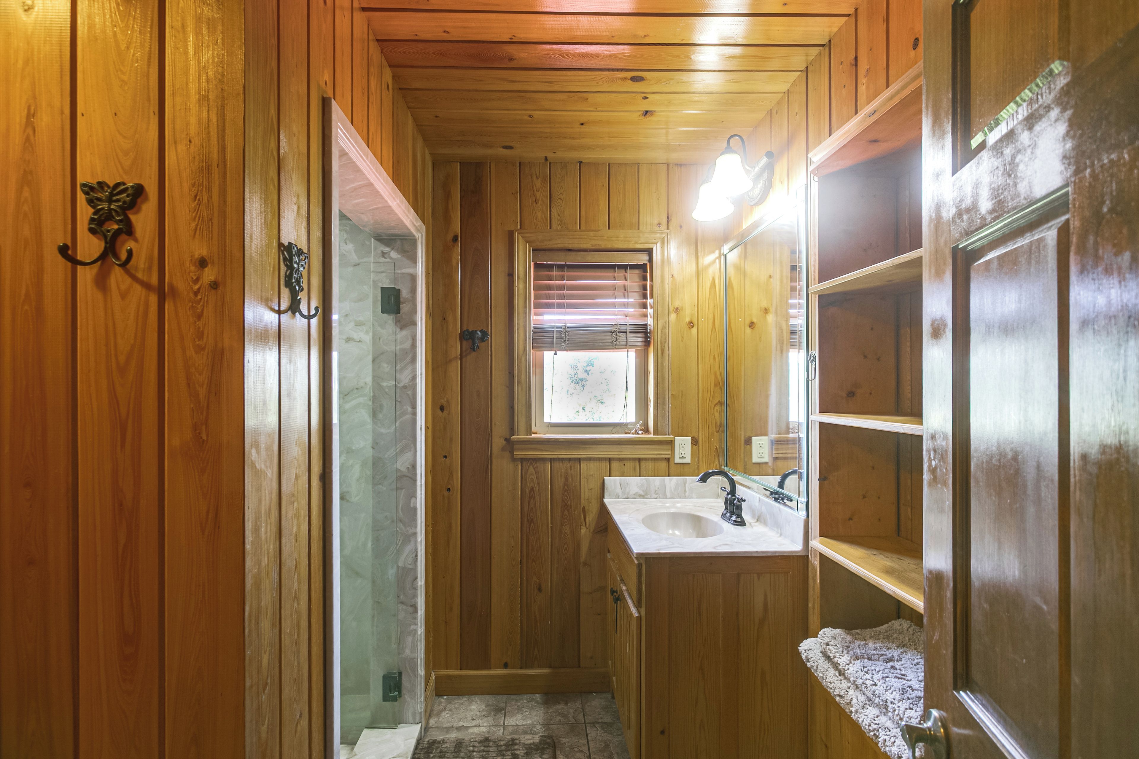 A wooden-paneled bathroom with a sink, mirror, and towel rack.