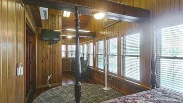 A room with wooden walls, a ceiling fan, a television mounted on the wall, and a patterned carpet.