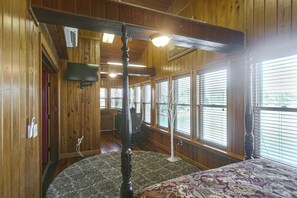 A room with wooden walls, a ceiling fan, a television mounted on the wall, and a patterned carpet. - Georgia Cabin Escape on 500 Acres (Nashville)