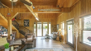 A spacious living room with a wooden interior, a sofa, a coffee table, and a staircase. - Georgia Cabin Escape on 500 Acres (Nashville)