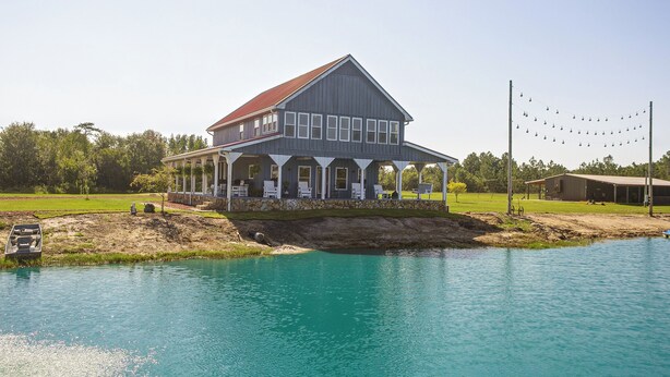 A large two-story house with a porch, a swimming pool, and a dock extending into the water. - Georgia Cabin Escape on 500 Acres (Nashville)