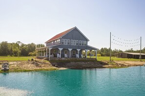 A large two-story house with a porch, a swimming pool, and a dock extending into the water. - Georgia Cabin Escape on 500 Acres (Nashville)