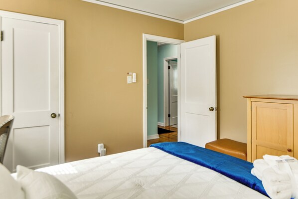 A hotel room with a bed, a wooden bench, a wardrobe, and a door leading to another room.