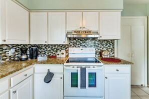 A kitchen with white cabinets, a stainless steel range hood, a coffee maker, and a 'Welcome' sign above the cabinets.
