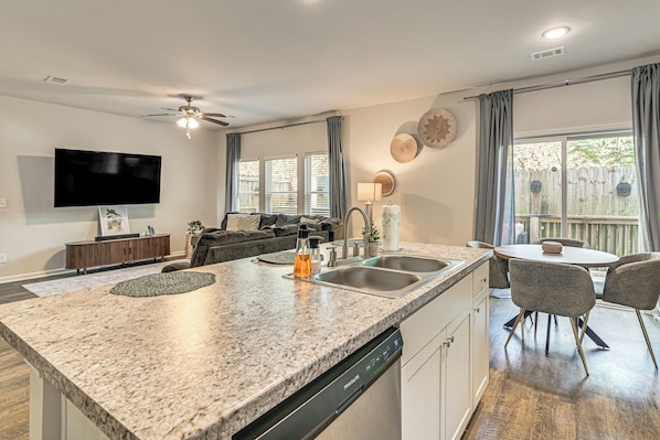 A modern kitchen with granite countertops, a dishwasher, and a dining area with a table and chairs.