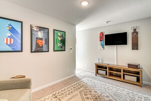 Un salon doté d’un téléviseur à écran plat fixé au mur, d’un meuble de rangement en bois et de trois affiches encadrées accrochées au mur.