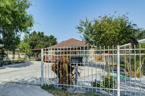 A fenced yard with a mailbox, a red vehicle, and a house with a brown roof.