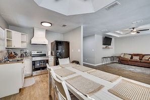 A modern kitchen with a built-in oven, refrigerator, and a dining area with a table and chairs.