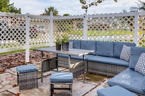 A patio with a sectional sofa, two chairs, a small table, and potted plants. - Boat Ramp, Fishing Pier & Game Room Retreat (Edgewater)