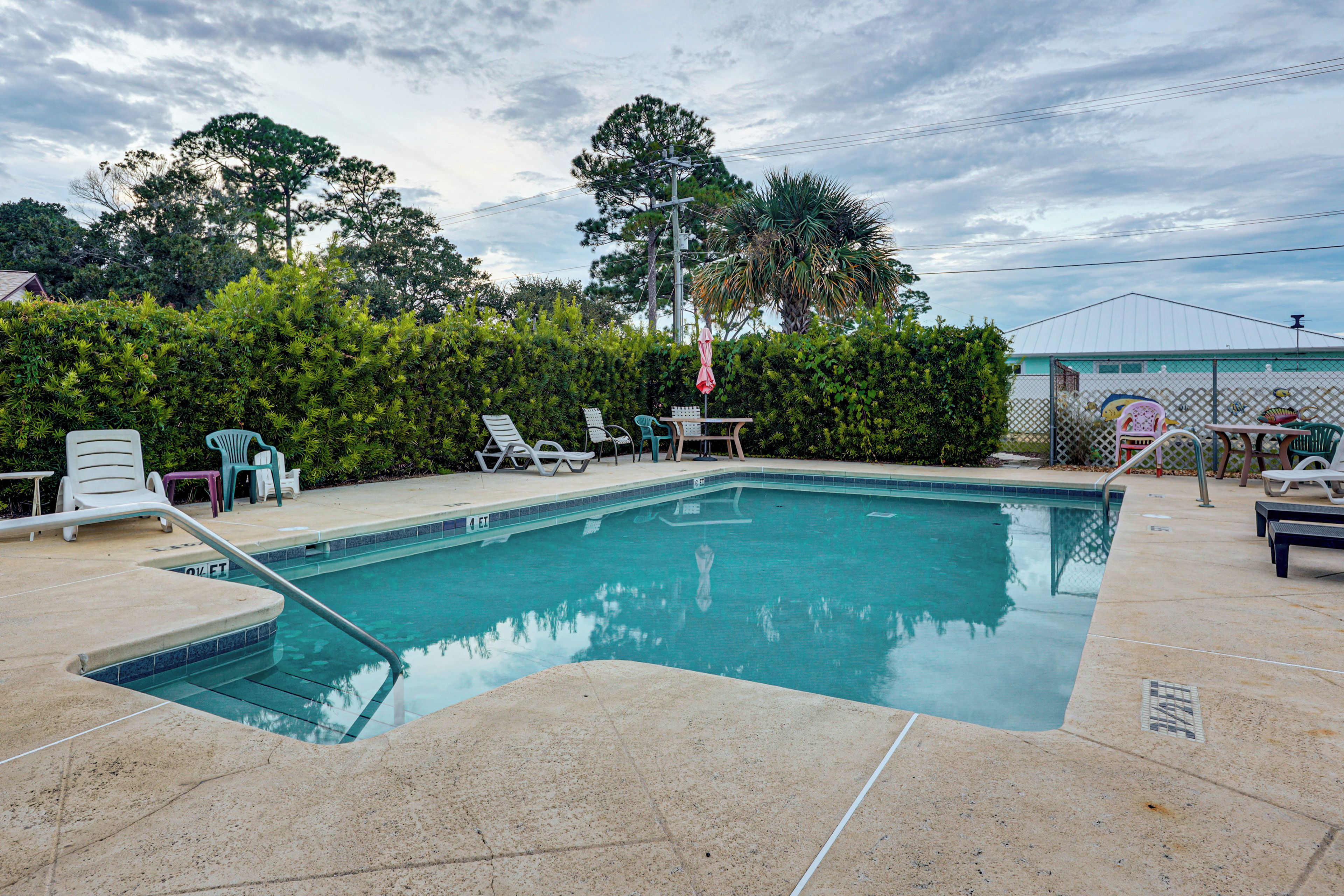 A swimming pool with lounge chairs and a fence.