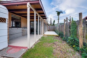 A covered outdoor area with a concrete floor, a wooden fence, and a grassy patch. - Boat Ramp, Fishing Pier & Game Room Retreat (Edgewater)