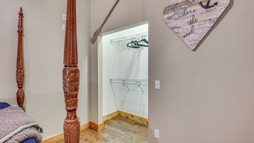 A bedroom with a wooden bed frame, a hanging clothes rack, and a heart-shaped wall decoration.