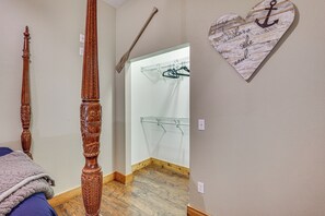 Quarto com estrutura de cama de madeira, um cabideiro e um ornamento de coração na parede.