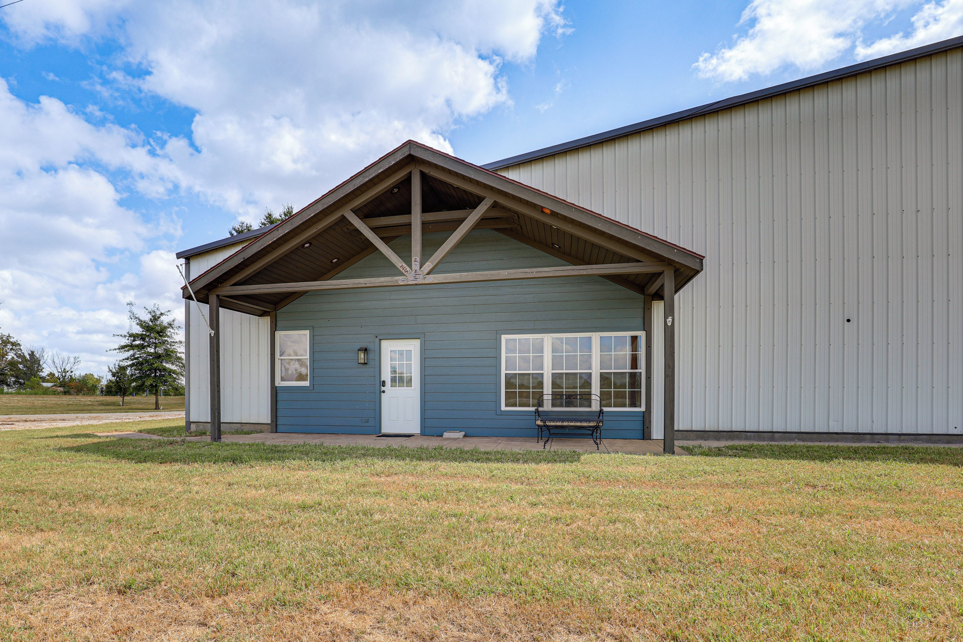 A single-story building with a gabled roof, a front door, and a bench outside.
