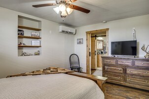 Un dormitorio con cama, cómoda, silla, televisor y ventilador de techo.