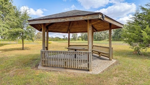 Un gazebo in legno con base in pietra, panchine e ringhiera.