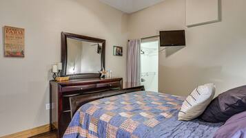 Un dormitorio con una cama, un aparador, un espejo, un televisor y una pared con un cartel.