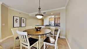 Een eetgedeelte met een ronde tafel, witte stoelen en een hanglamp.
