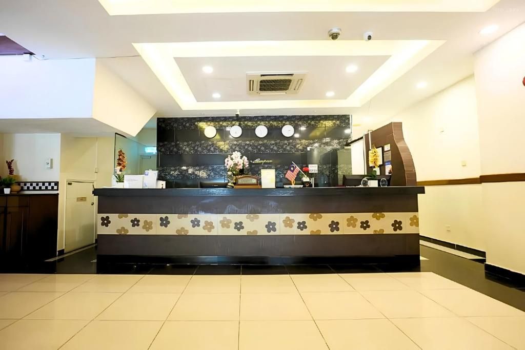 A hotel reception area with a reception desk, a clock, and a plant.