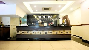 Un espace d’accueil d’hôtel comprenant un comptoir de réception, une horloge et une plante.