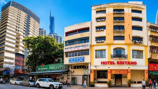 Un hôtel à plusieurs étages, reconnaissable à son enseigne bien visible, entouré d’autres bâtiments et avec un ciel dégagé.