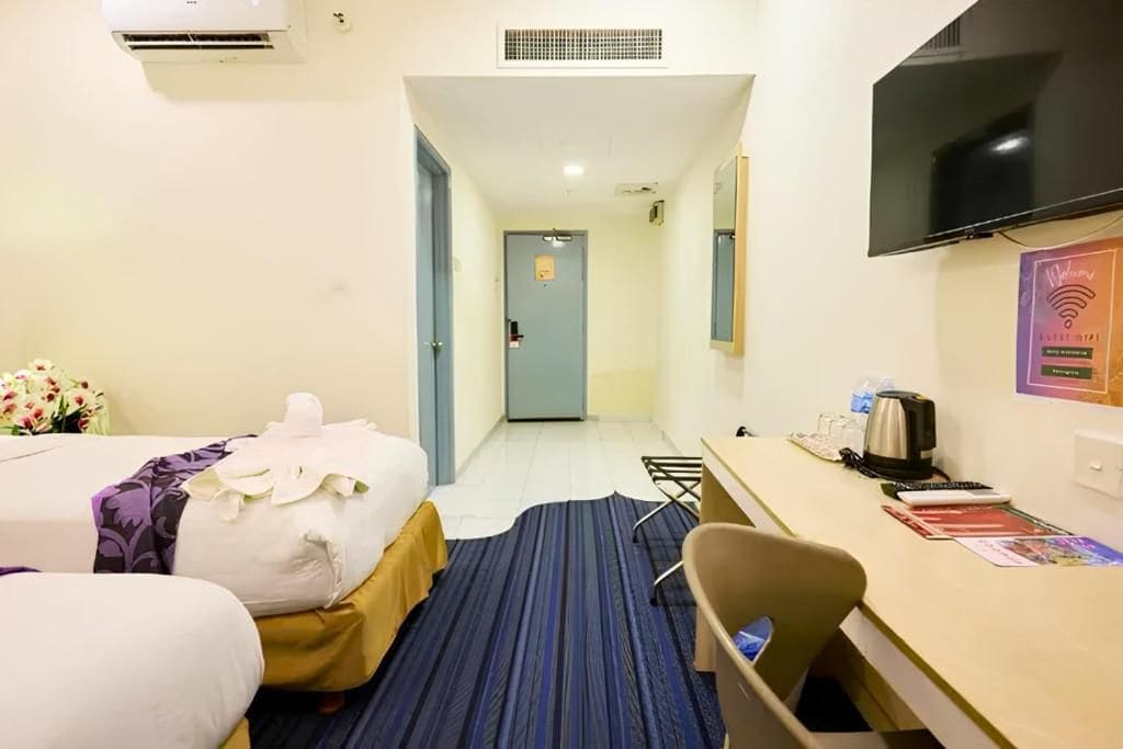 Une chambre d’hôtel avec deux lits, un bureau, une chaise, une télévision et une porte de salle de bain.