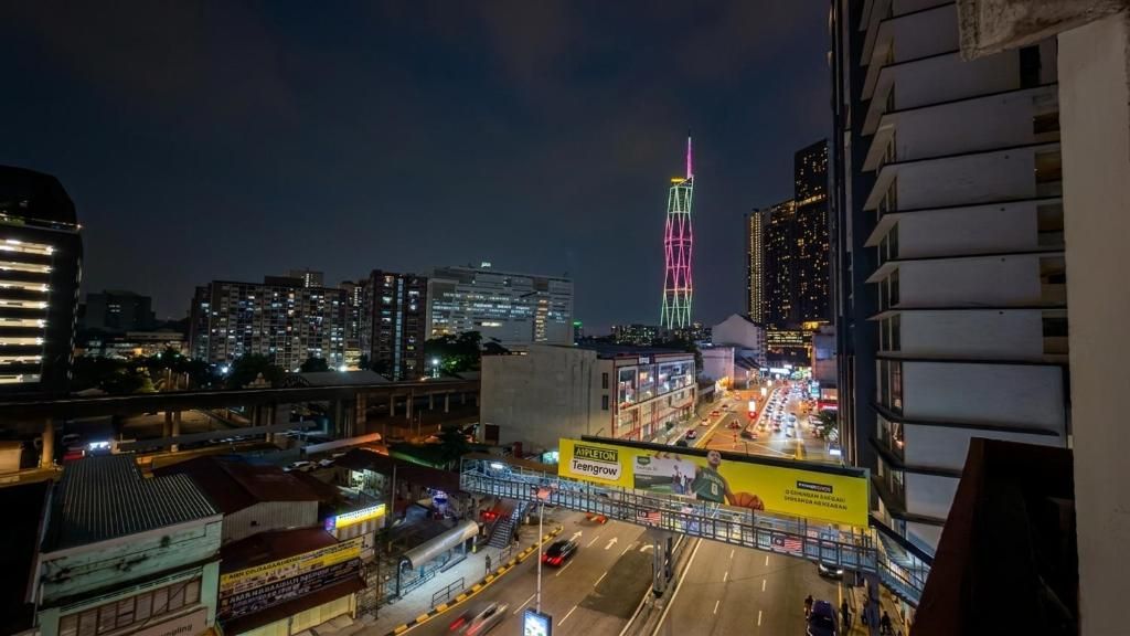 A nighttime cityscape with illuminated buildings and a prominent tower with colorful lights.