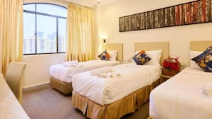 Une chambre d’hôtel avec deux lits, un bureau et une grande fenêtre avec des rideaux.