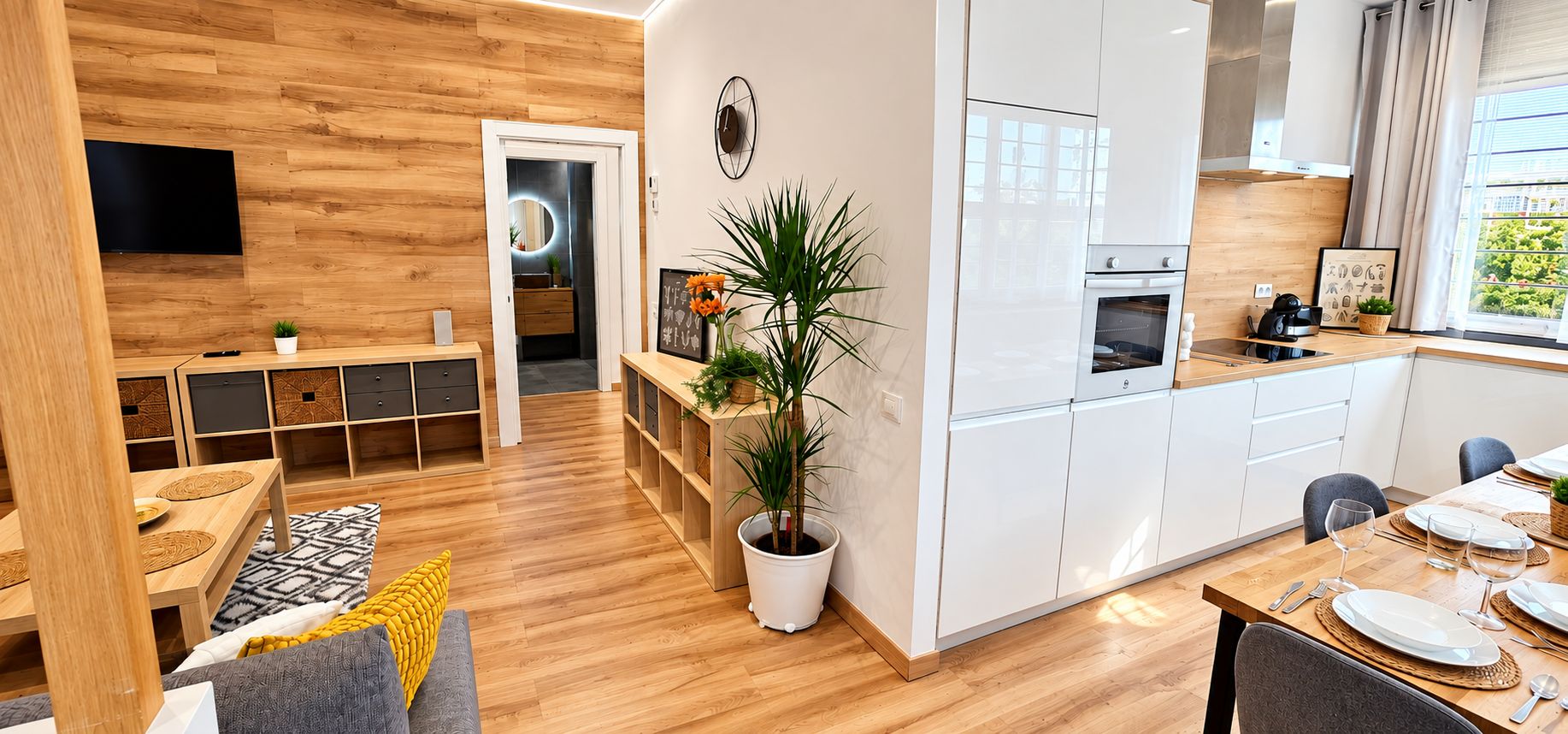 Een moderne keuken met witte kasten, een houten aanrecht en een eethoek met een tafel gedekt voor twee personen.
