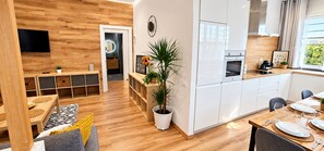 Une cuisine moderne avec des meubles blancs, un plan de travail en bois et un coin repas avec une table dressée pour deux personnes.