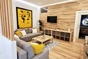 Un salon moderne avec un canapé gris, des coussins jaunes, une table basse et un meuble en bois doté de tiroirs.
