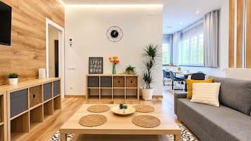 Un salon moderne avec un canapé gris, une table basse en bois et un téléviseur fixé au mur.