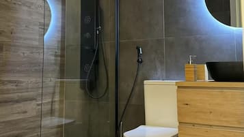 Une salle de bain moderne avec une douche à parois de verre, des toilettes et un meuble-lavabo en bois avec un évier.